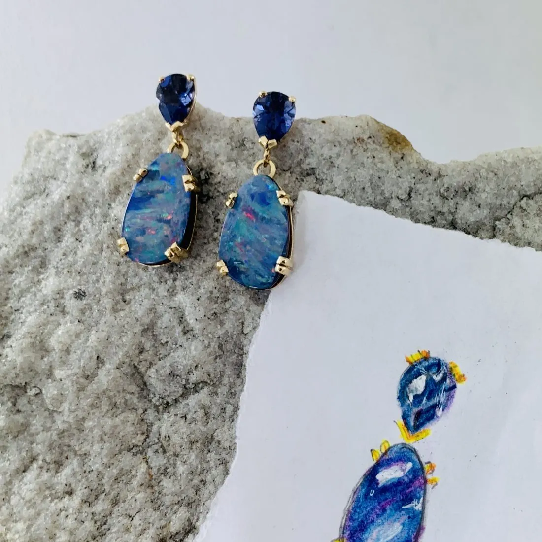 Ellen's watercolor sketch beside the finished opal and sapphire drop earrings it became